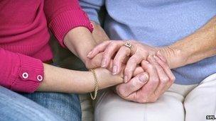 A carer and patient hold hands