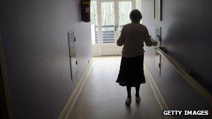 A dementia sufferer walks down a care home corridor.