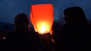 People lighting a lantern in Osmaston Park in Derby