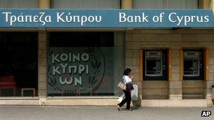 A woman passes outside a branch of Bank of Cyprus in the main shopping street in central capital Nicosia, Cyprus