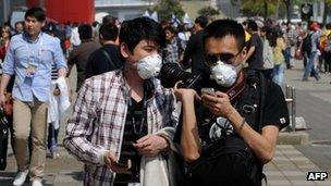 People wear facemasks due to the recent outbreak of bird flu as fans arrive before the start of the Formula One Chinese Grand Prix in Shanghai on 14 April 2013