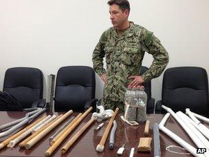 Navy Capt Robert Durand stands with makeshift weapons recovered from inmates after clashes on 16 April