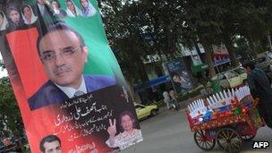 An ice cream vendor passes by an election banner for Mr Zardari in March 2013