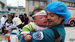 A Chinese medical worker holds an injured child in Longmen, a town close to the epicentre of the earthquake that hit the city in Ya'an, south-west China's Sichuan province, 21 April 2013