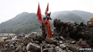 A rescue worker stands beside a truck crushed by a landslide, after Saturday's earthquake, near Lingguan town of Baoxing county, Sichuan province, 22 April 2013