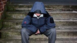 Teenager in hood sits on steps