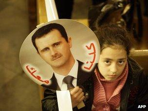 A Syrian girl carries a picture of Bashar al-Assad saying "we are with you" during a Mass at a Greek Orthodox church in Damascus (9 January 2012)