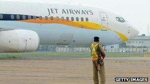 An Indian security official looks on as an aircraft of Jet Airways taxies after landing at Indira Gandhi International Airport in New Delhi