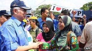 Malaysia's Prime Minister Najib Razak (L), president of the ruling party National Front, shakes hands with supporters in Kuala Lumpur