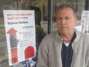 Businessman Tom Murray next to a poster opposing residents' parking in Bishopston