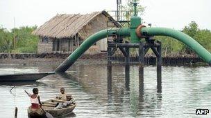 Children in a boat pass an oil pipeline head near their home in Rivers state April 2011