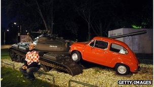 A museum display of a tank crushing a small car depicting a scene from Croatia's war of independence