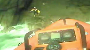 Two RNLI crewmen climb rocks