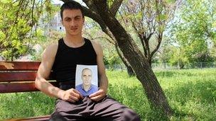 Txumir Arsenov holds up a picture of his father, who killed himself in protest