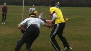 Two players try to grab a tag from the clothes of a man dressed in yellow