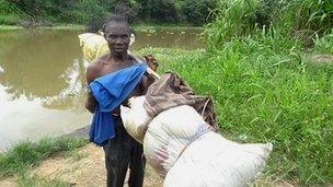 Jeti Matikmo, fisherman carrying a pole on his shoulder with bundles of fish