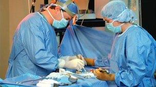 A surgeon and a nurse perform an operation