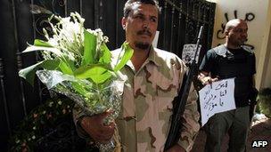 A Libyan security guard carries flowers for Stevens