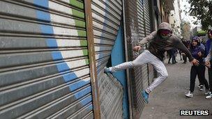 Protester kicks a store's shutter during a rally in Santiago (11 April 2013)