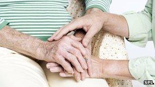 Person holds elderly woman's hand