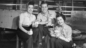 Two women and one man take a break while working in a factory.