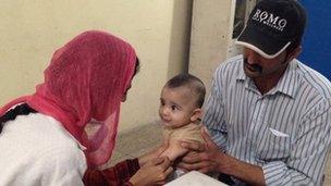 Family getting a measles vaccination for their child at a hospital in Lahore