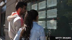 Two people look at job announcements on the window of an agency in Naples