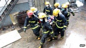 Chinese firefighters evacuate an injured worker from the Baoyuan poultry plant that caught fire in Dehui, north-east China's Jilin province on Monday