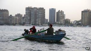 An Egyptian woman rows a boat with her family along the Nile River, in Cairo