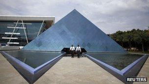 Employees walk in front of a pyramid-shaped building at the Infosys campus in the Electronic City area of Bangalore in this September 4, 2012 file photo.