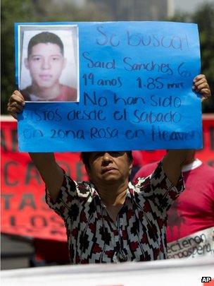 A woman holds up a sign describing one of the missing on 30 May 2013