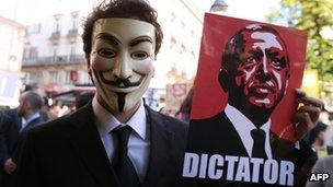 A masked protester holds a picture of Turkish PM Recip Tayyip Erdogan in Paris.