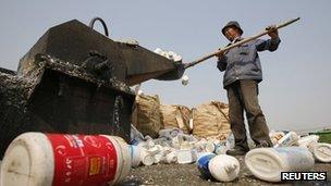 A worker shovels plastic bottles into a shredder at a recycling depot in Beijing 26 April 2013