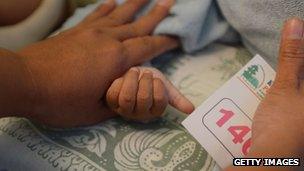 Woman holding girl's hand as she is circumcised in Indonesia