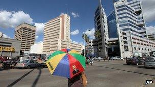 A woman with an umbrella bearing the image of US President Barack Obama in Harare, Zimbabwe, on 10 May 2013