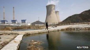 A worker walks past the chimneys of a steel factory in Beijing April 1, 2013.