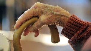 Elderly lady's hand on walking stick