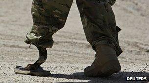 A Nato soldier walks with an artificial limb to board a Chinook helicopter after a security handover ceremony at a military academy outside Kabul, 18 June 2013