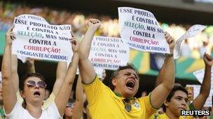 Protesters cheer as they hold signs during the Confederations Cup Group A soccer match between Brazil and Mexico