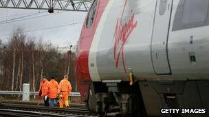 As a Virgin pendolino train passes workers from Network Rail check points and track at Crewe Grand Junction on the West Coast mainline