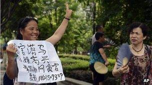 A woman holds up an anti-corruption sign outside the court where Lei Zhengfu was tried (19 June 2013)