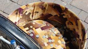 Coins lay in a buskers collection basket