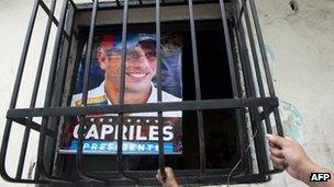 Supporters of Venezuelan opposition presidential candidate Henrique Capriles have a poster with his picture at their home in the Petare slum in Caracas on April 13