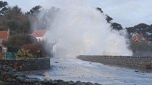 Waves crash over the sea wall at Perelle