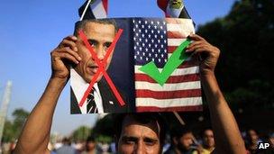 An opponent of Egypt's Islamist President Mohammed Morsi holds up a picture showing the United States President Barack Obama and US flag during a rally outside the Presidential palace in Cairo, Egypt, 7 July 2013