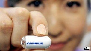 An Olympus employee holding a capsule type endoscope