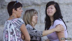 A crying woman is comforted by two others at the Sainte-Agnes Church following the train disaster in Lac-Megantic