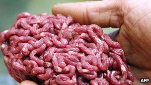 A man holds minced beef meat