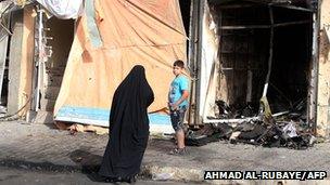 Iraqis look at destroyed shops following a car bomb in the Topchi neighbourhood of northern Baghdad (July 21, 2013)