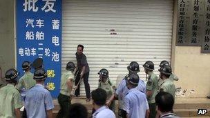 In this 23 July 2013 photo, Chinese security personnel try to subdue a knife-wielding man outside the family planning office in Dongxing city in southwest China's Guangxi province